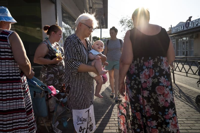 A woman holds a baby as she walks down a street in the Black Sea resort of Sochi, Russia, Friday, Sept. 15, 2023