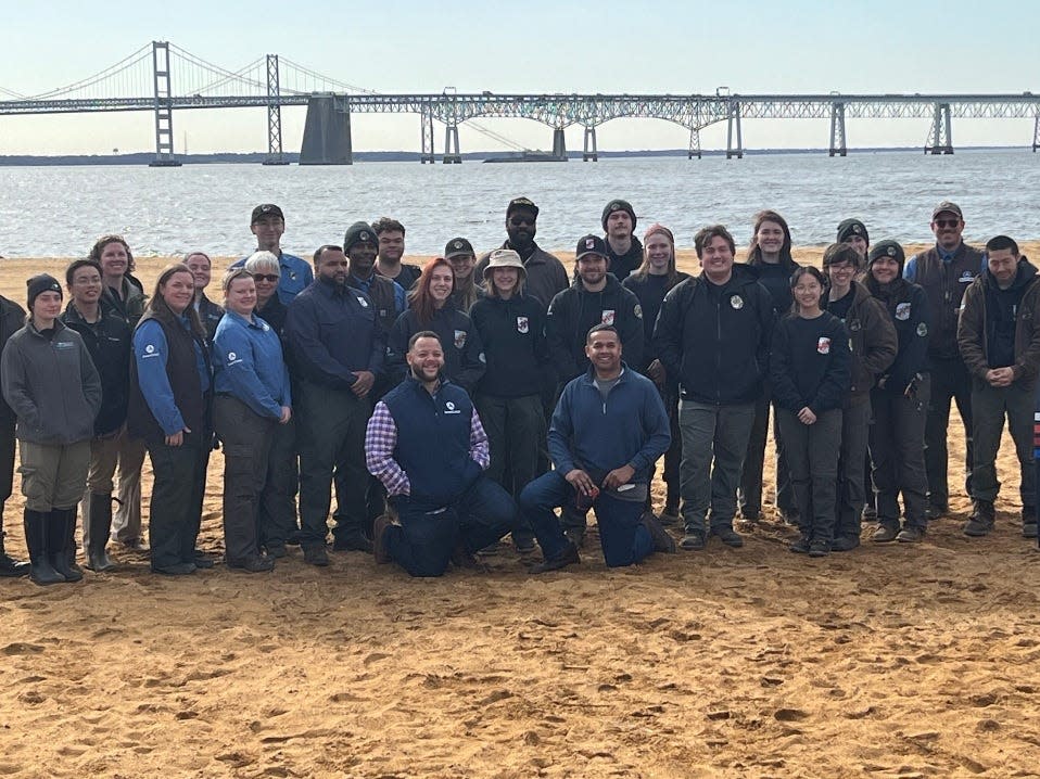 Members of the Maryland Conservation Corps and others pose for a photograph on the beach at Sandy Point State Park in Annapolis on March 12, 2024.
