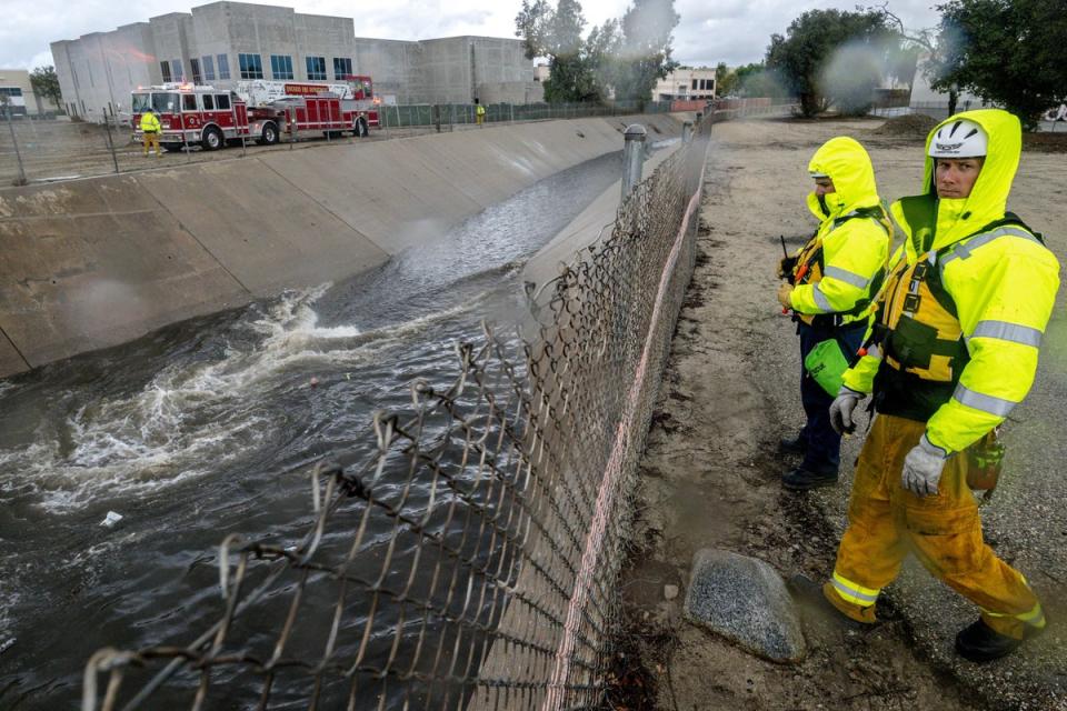 Firefighters look for people trapped in the rain-swollen Cucamonga wash in Ontario (© 2022, The Press-Enterprise/SCNG)