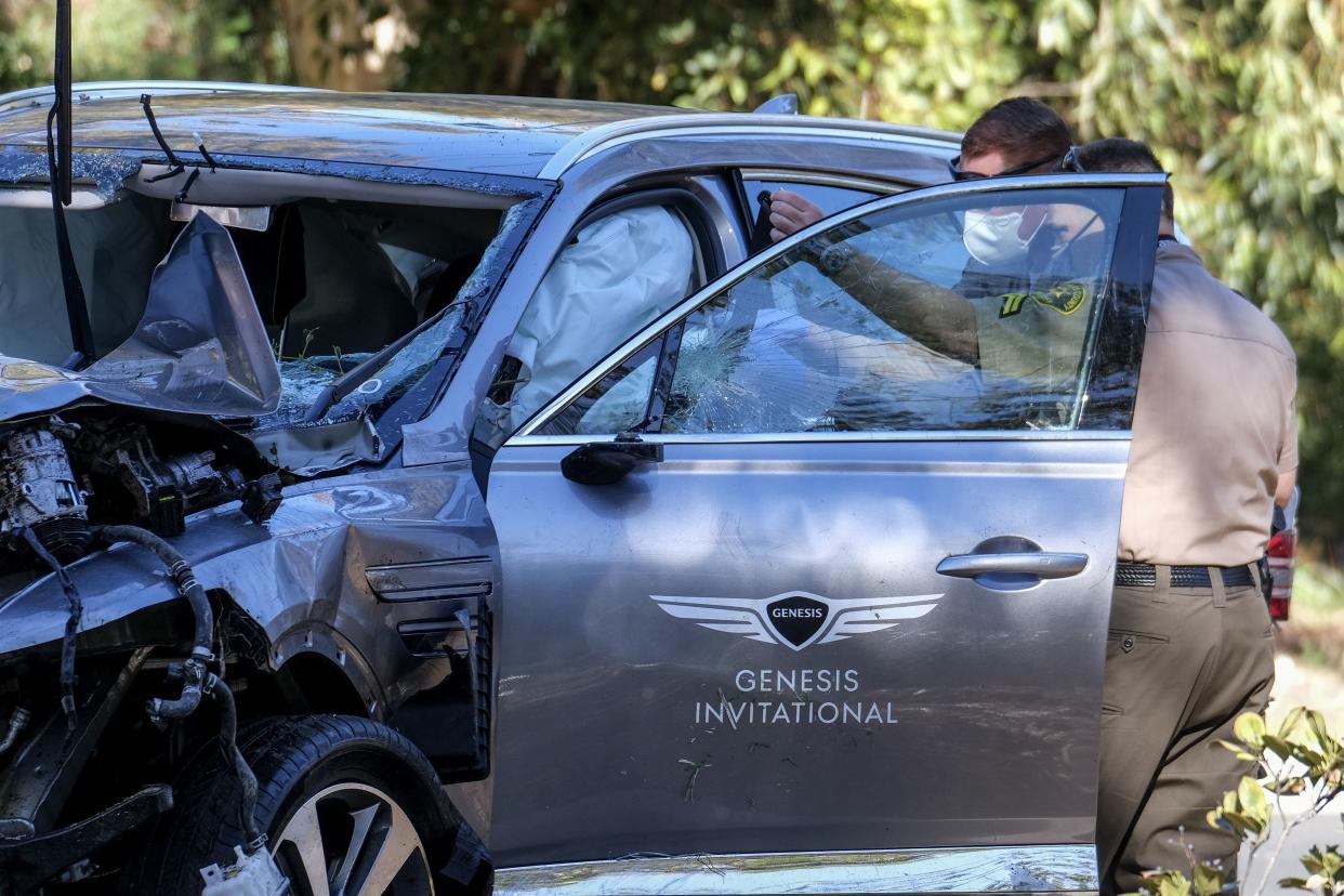 Law enforcement officers look over a damaged vehicle following a rollover accident involving golfer Tiger Woods, Tuesday, Feb. 23, 2021, in the Rancho Palos Verdes suburb of Los Angeles.