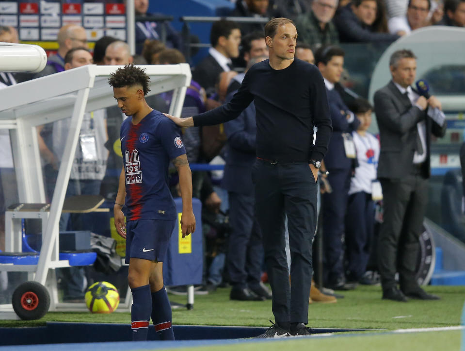 PSG's Thilo Kehrer, left, is patted on the back by PSG's coach Thomas Tuchel as he leaves the field during the French League One soccer match between Paris-Saint-Germain and Monaco at the Parc des Princes stadium in Paris, Sunday April 21, 2019. (AP Photo/Michel Euler)