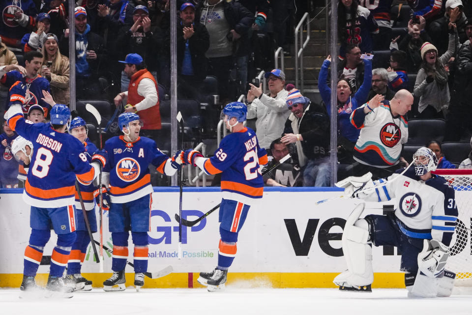 Winnipeg Jets goaltender Connor Hellebuyck (37) reacts as the New York Islanders celebrate a goal by Sebastian Aho during the first period of an NHL hockey game Wednesday, Feb. 22, 2023, in Elmont, N.Y. (AP Photo/Frank Franklin II)