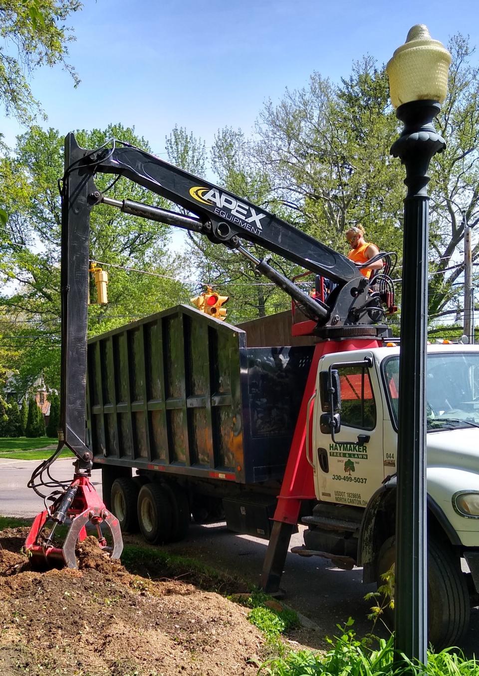 Aaron Bowersox of Haymaker Tree & Lawn Service claws away at an old stump Thursday at West Exchange Street and Elmdale Avenue in Akron.