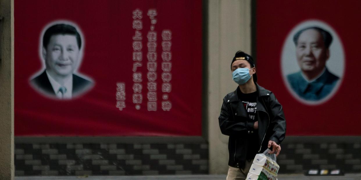 FILE PHOTO: A man wearing a mask walks by portraits of Chinese President Xi Jinping and late Chinese chairman Mao Zedong as the country is hit by an outbreak of the novel coronavirus, on a street in Shanghai, China February 10, 2020. REUTERS/Aly Song