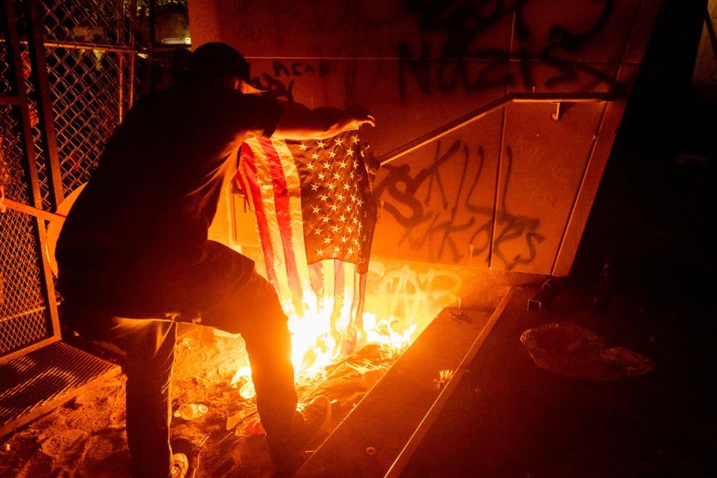 A Black Lives Matter protester burns an American flag outside the Mark O. Hatfield United States Courthouse in July 2020  (AP)