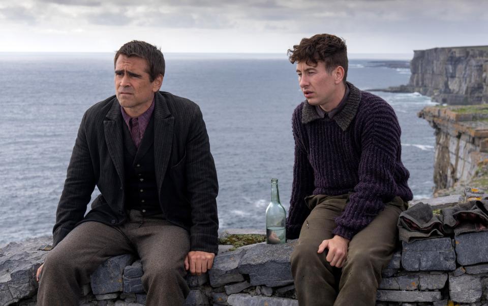 Colin Farrell and Barry Keoghan sit on a rock wall in a scene from The Banshees of Inisherin