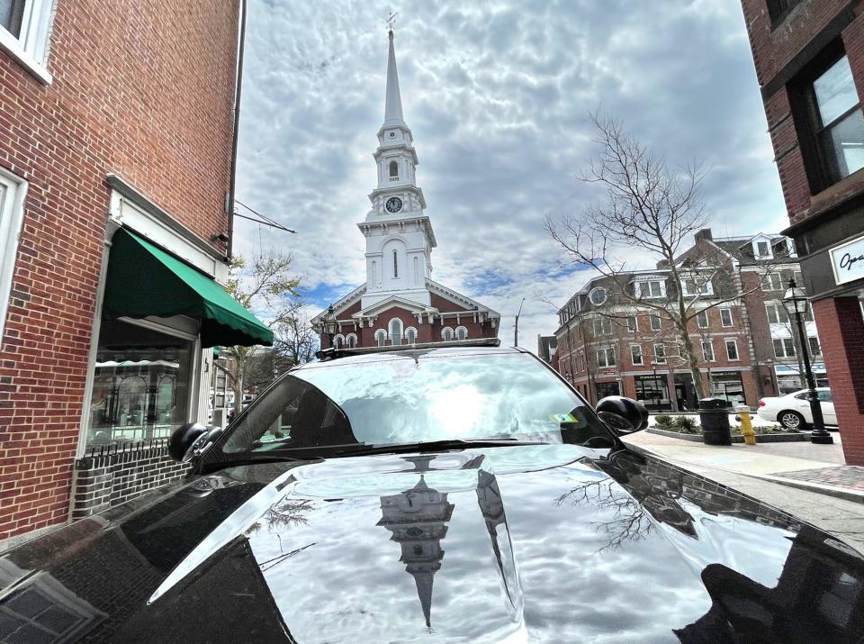 The North Church steeple is reflected in the hood of a Portsmouth police cruiser parked on High Street in Market Square Monday, April 29, 2024.