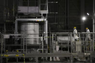 FILE - In this Feb. 12, 2020, photo, two workers wearing hazmat suits work at a water treatment facility at the Fukushima Dai-ichi nuclear power plant in Okuma, Fukushima prefecture, northeastern Japan. The head of the wrecked Fukushima nuclear plant said Tuesday, March 2, 2021 there's no need to extend the current target to finish its decommissioning in 30-40 years despite uncertainties about melted fuel inside the plant's three reactors. (AP Photo/Jae C. Hong, File)