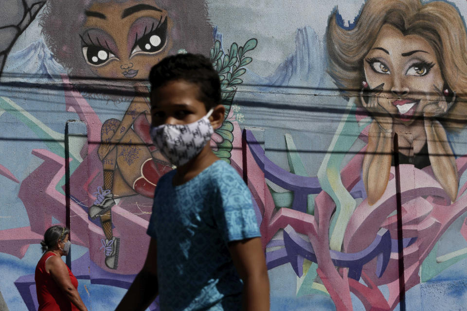 People wear masks amid the COVID-19 pandemic in Ceilandia, one of the neighborhoods most affected by COVID-19 in Brasilia, Brazil, Tuesday, July 21, 2020. (AP Photo/Eraldo Peres)