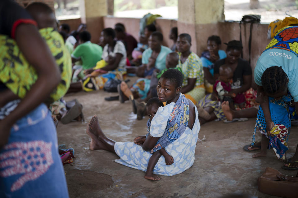 In this photo taken Wednesday Dec. 11, 2019, residents of the Malawi village of Tomali wait to have their young children become test subjects for the world's first vaccine against malaria. Babies in three African nations are getting the first and only vaccine for malaria in a pilot program. World health officials want to see how well the vaccine works in Malawi, Ghana and Kenya before recommending its wider use. (AP Photo/Jerome Delay)