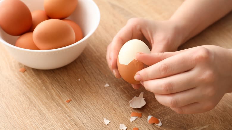 hands peeling an egg