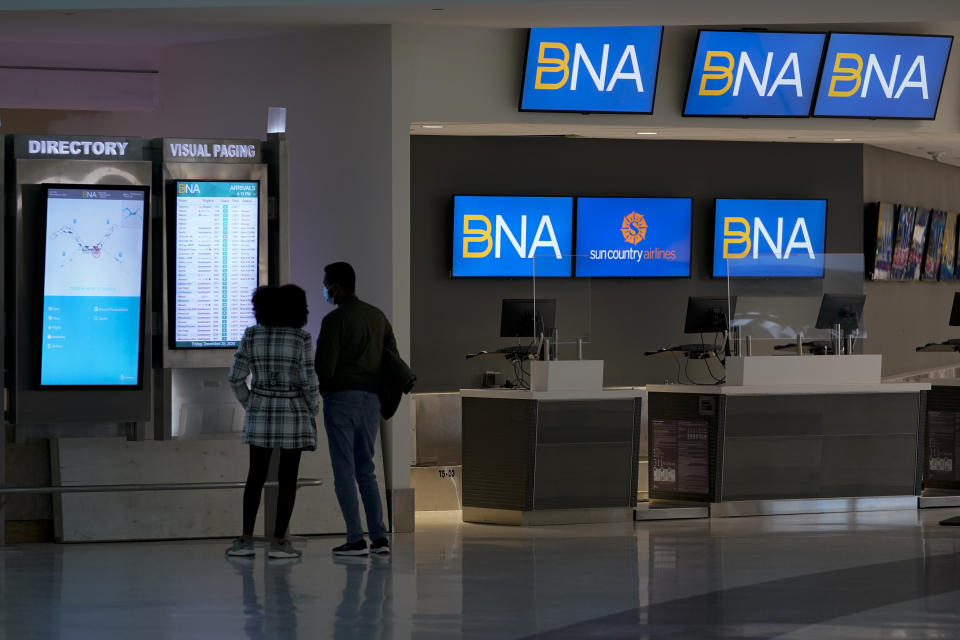 A couple checks flight status at Nashville international Airport Friday, Dec. 25, 2020 in Nashville. Tenn. Flights were impacted because of telecommunications issues associated with explosion in downtown. (AP Photo/Mark Humphrey)