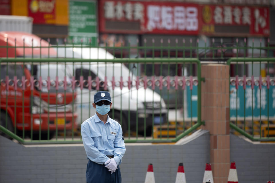 A security officer stands guard outside the Xinfadi wholesale food market district in Beijing, Saturday, June 13, 2020. Beijing closed the city's largest wholesale food market Saturday after the discovery of seven cases of the new coronavirus in the previous two days. (AP Photo/Mark Schiefelbein)