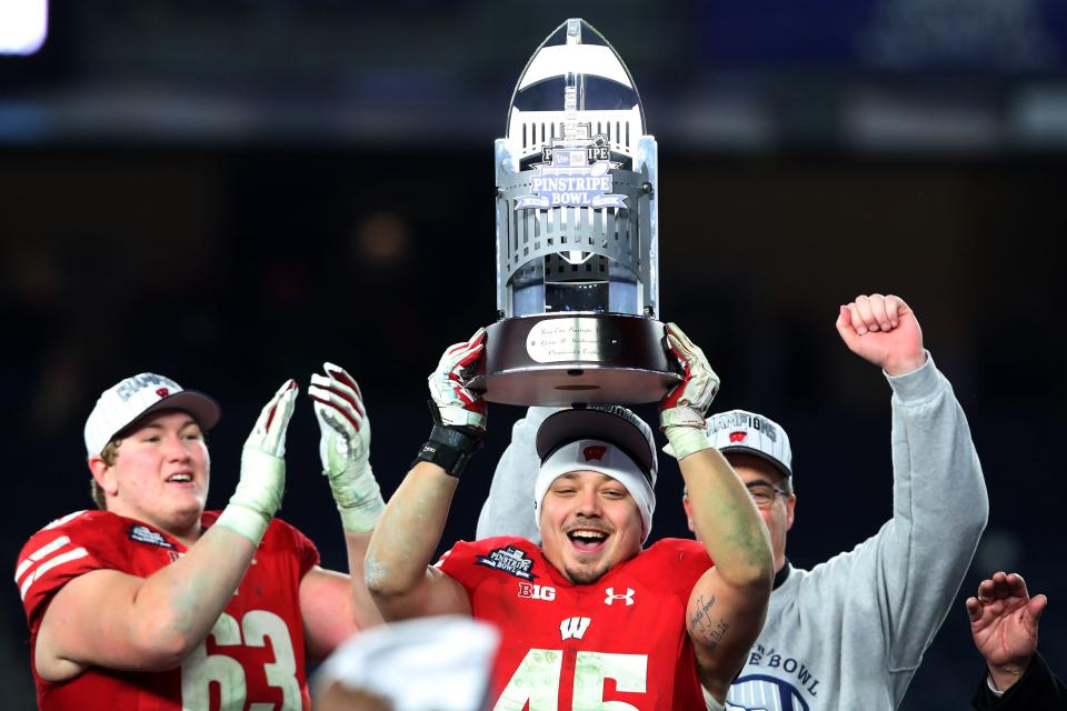 Fullback Alec Ingold holds up the 2018 Pinstripe Bowl trophy after the Badgers beat Miami, 35-3, at Yankee Stadium in 2018.