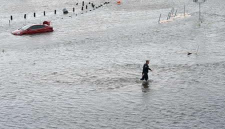 A police officer wades through the Hurricane Harvey floodwaters in Alvin, Texas August 29, 2017. REUTERS/Rick Wilking