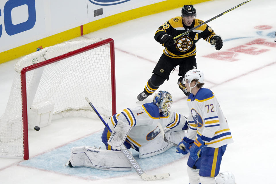 Boston Bruins left wing Brad Marchand (63) celebrates after teammate Charlie Coyle scored the game-winning goal past Buffalo Sabres goaltender Ukko-Pekka Luukkonen (1) during overtime of an NHL hockey game, Saturday, Jan. 1, 2022, in Boston. (AP Photo/Mary Schwalm)