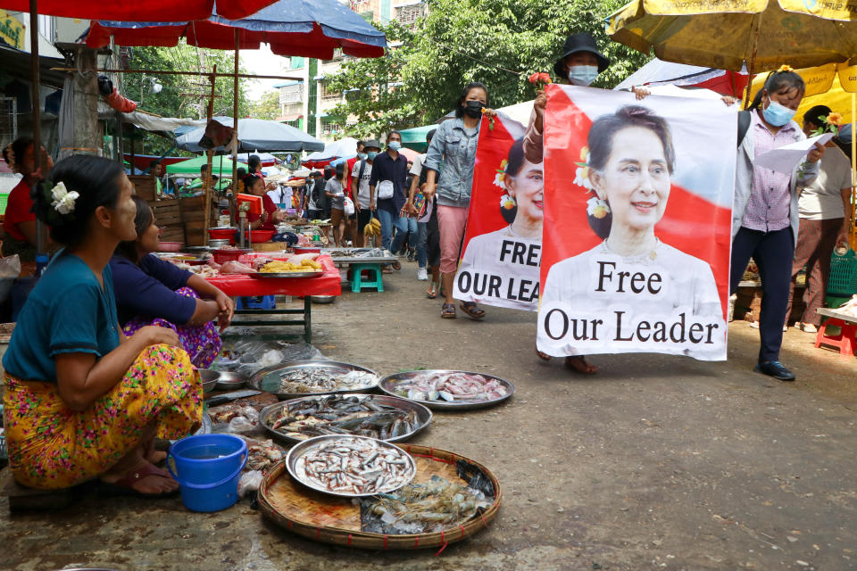 FILE - Anti-coup protesters walk through a market with images of ousted Myanmar leader Aung San Suu Kyi in Yangon, Myanmar, April 8, 2021. As Feb. 1, 2023, marks two years after Myanmar’s generals ousted Aung San Suu Kyi’s elected government, thousands of people have died in civil conflict and many more have been forced from their homes in a dire humanitarian crisis. (AP Photo, File)