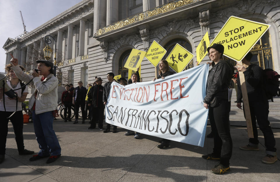 Members of the Housing Rights Committee of San Francisco and other activists protest outside of City Hall in San Francisco, Tuesday, Jan. 21, 2014. San Francisco officials are set to vote on a plan to start regulating employee shuttles for companies like Google, Facebook and Apple, charging a fee for those that use public bus stops and controlling where they load and unload. Private shuttle buses have created traffic problems, blocking public bus stops during peak commute hours. (AP Photo/Jeff Chiu)