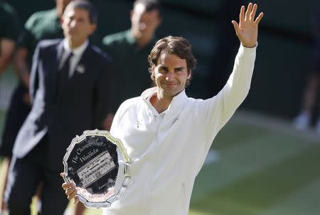 Roger Federer of Switzerland waves while holding the runner-up's trophy after being defeated by Novak Djokovic of Serbia in their men's singles finals tennis match on Centre Court at the Wimbledon Tennis Championships in London July 6, 2014. REUTERS/Suzanne Plunkett