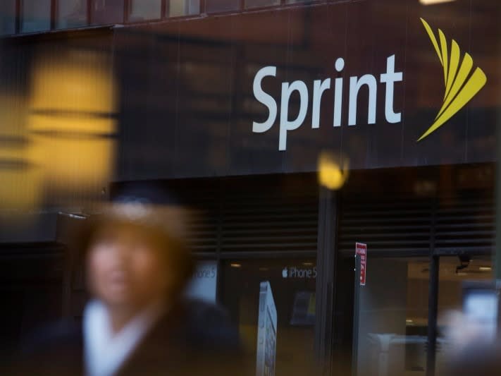 People walk past a Sprint store in New York in this file photo taken December 17, 2012. REUTERS/Andrew Kelly/Files