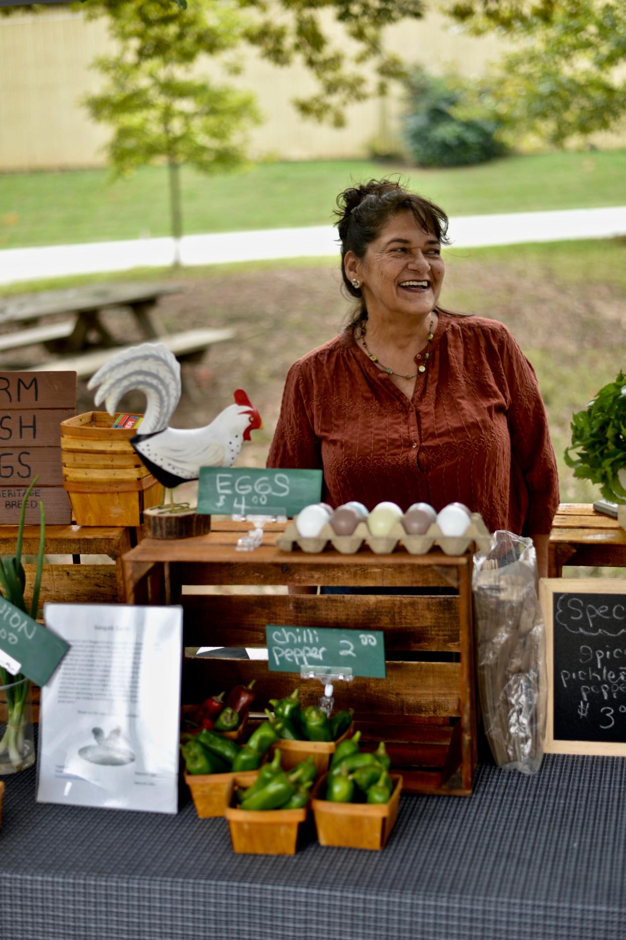 Lydia Engelsen stands behind her booth, chatting and laughing with patrons at the Marigold Market in Winterville, Georgia, on Oct. 2, 2021.