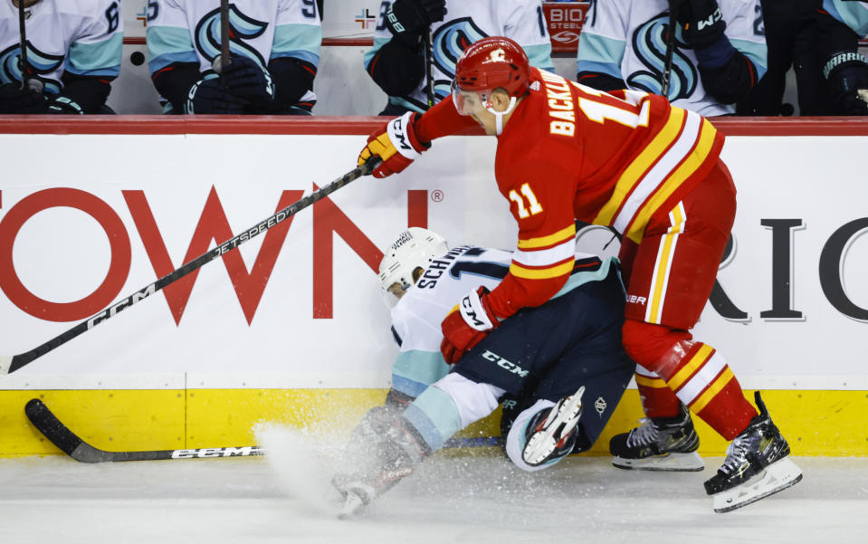 Seattle Kraken forward Jaden Schwartz, left, is checked by Calgary Flames forward Mikael Backlund during the first period of an NHL hockey game, Tuesday, Nov. 1, 2022 in Calgary, Alberta. (Jeff McIntosh/The Canadian Press via AP)