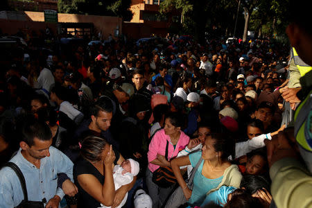 A woman carrying a baby, reacts while she queues on the street as she trys to buy diapers outside a pharmacy in Caracas, Venezuela March 18, 2017. REUTERS/Carlos Garcia Rawlins