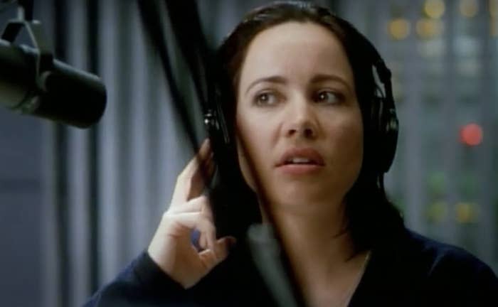 Actor Janeane Garofalo has headphones on and speaks into a microphone.