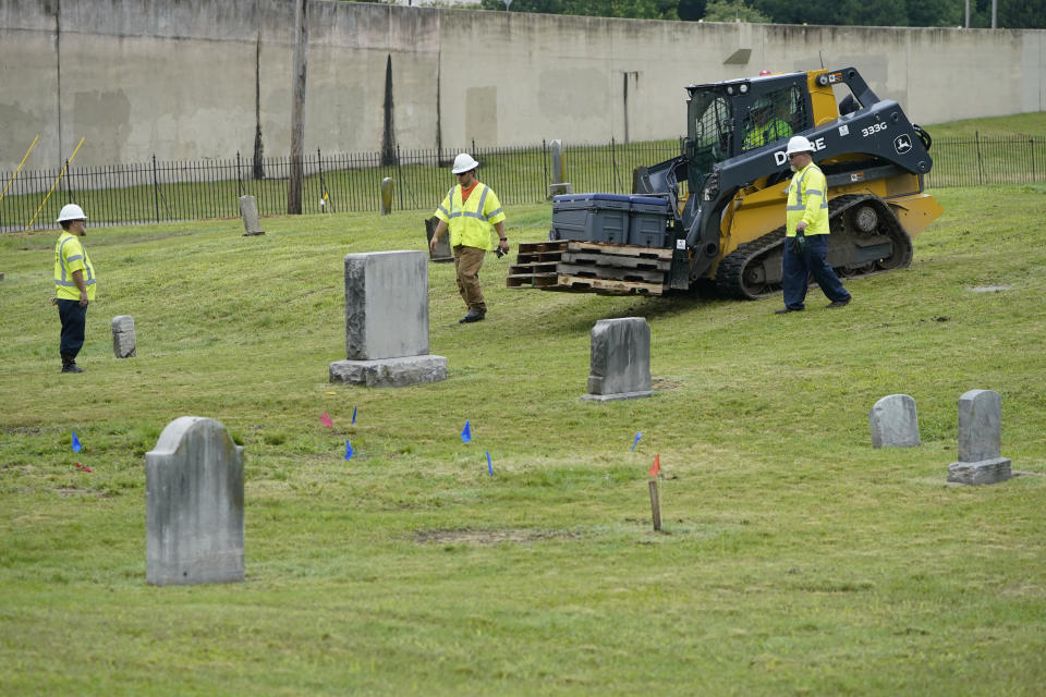 Workers bring equipment to the site where excavation will take place at Oaklawn Cemetery in a search for victims of the Tulsa Race Massacre believed to be buried in a mass grave, Tuesday, June 1, 2021, in Tulsa, Okla. (AP Photo/Sue Ogrocki)