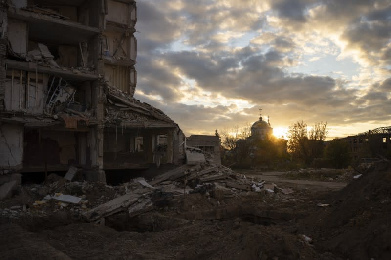 <cite>2023年10月24日，夕陽落在烏克蘭伊久姆一座被毀壞的建築物身後。（美聯社）</cite>