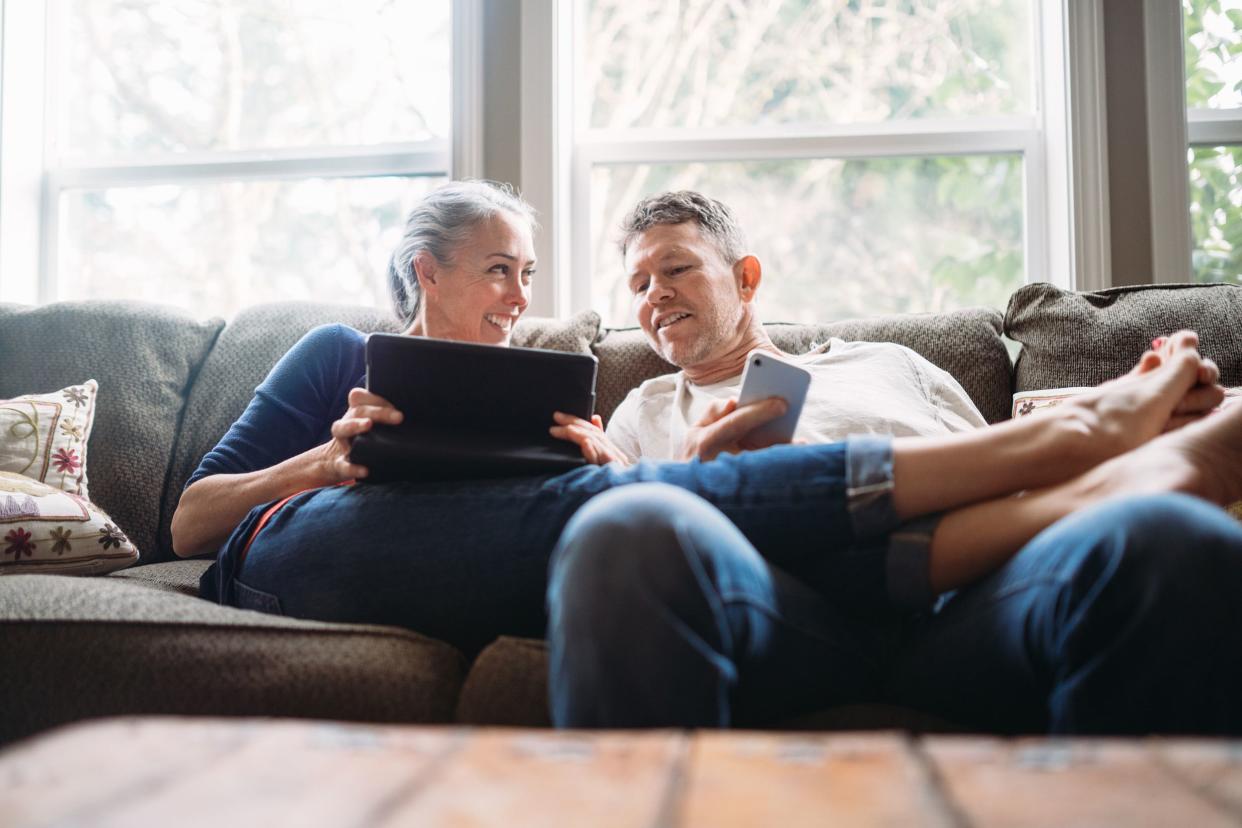 mature couple relaxing with tablet and smartphone