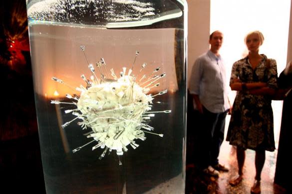 Visitors to the Hilario Galguera gallery in Mexico City contemplate a piece by Damien Hirst titled "The Sacred Heart of Jesus" consisting of a bulls heart pierced with assorted surgical instruments suspended in formaldehyde February 23, 2006.