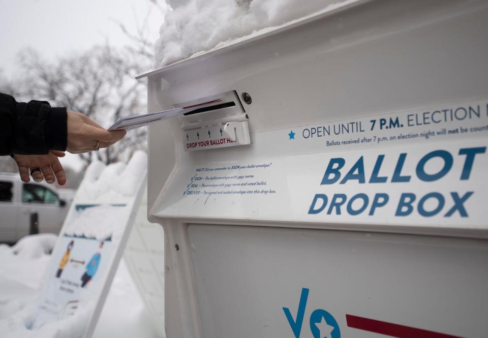 A voter drops ballots into the ballot box outside the Larimer County Courthouse in Fort Collins, Colo. on Monday, Oct. 26, 2020.