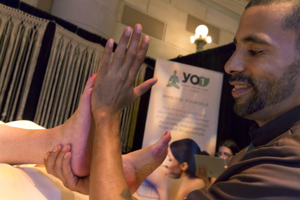 Massage Therapist Lenny Fore, from YO1 Luxury Nature Cure, in Monticello, N.Y., demonstrates a foot massage at the annual International Spa Association event, in New York, Tuesday, Aug. 7, 2018. (AP Photo/Richard Drew)