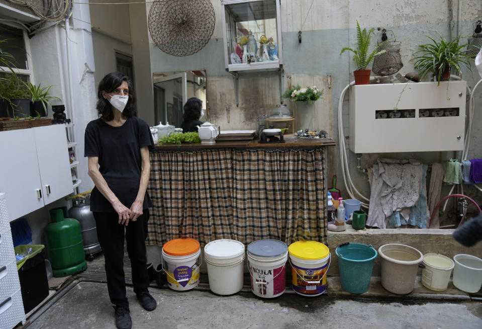 Rita Qadan, concierge of an office building, stands in her backyard which is close to the seaport, as she wears a face mask after the Lebanese Environment and Health Ministries warned residents living in neighborhoods near the Beirut Port to wear masks and to stay indoors, as one of its mammoth grain silos damaged in an August 2020 explosion may partially collapse, in Beirut, Lebanon, Thursday, July 28, 2022. Emmanuel Durand, a French civil engineer who volunteered for the Lebanese government-commissioned team of experts says it is inevitable that the north block going to collapse. (AP Photo/Hussein Malla)