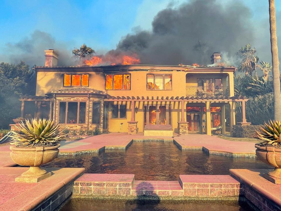 mansion with decorative pool plaza burning in smoky wildfire