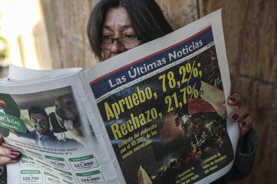 Una mujer lee un periódico que muestra los resultados del plebiscito del día anterior a favor de reescribir la Constitución de la nación en Santiago, Chile, el lunes 26 de octubre de 2020. (AP Foto/Esteban Felix)