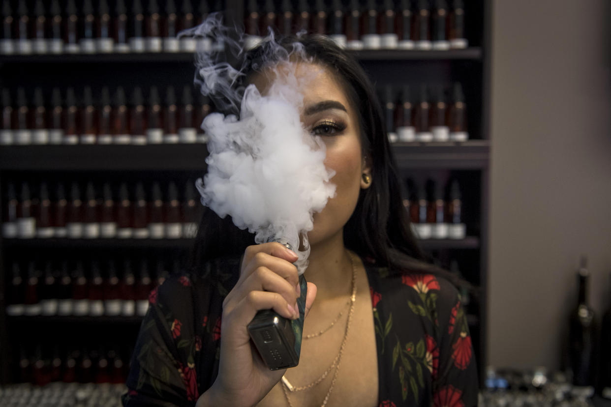 An employee using an electronic cigarette device at an e-cigarette store in Sacramento, US, on 28 June, 2018. (PHOTO: Bloomberg via Getty Images)