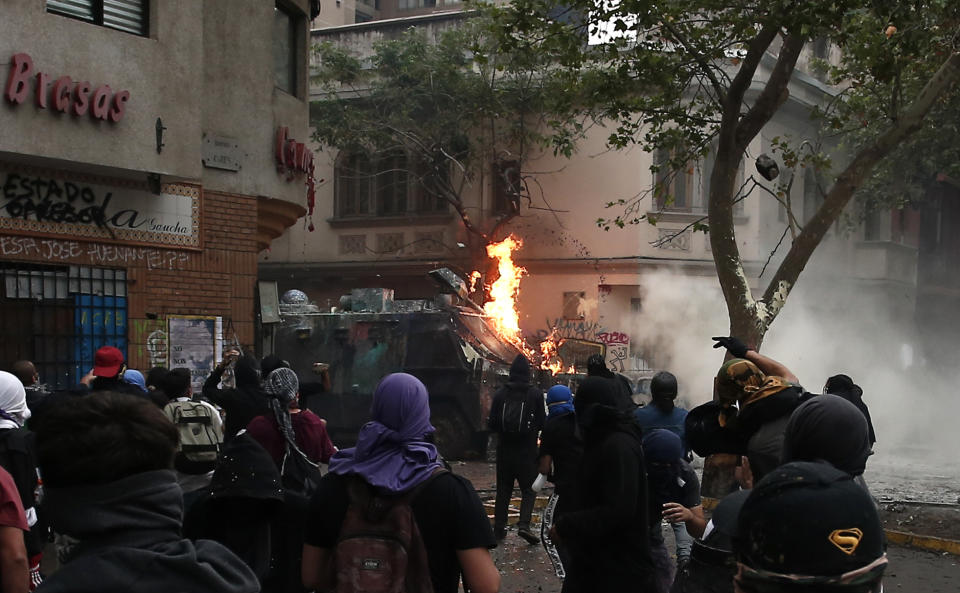 Anti-government protesters throw petrol bombs at a police truck in Santiago, Chile, Friday, Nov. 8, 2019. Chile's president on Thursday announced measures to increase security and toughen sanctions for vandalism following three weeks of protests that have left at least 20 dead. (AP Photo/Luis Hidalgo)