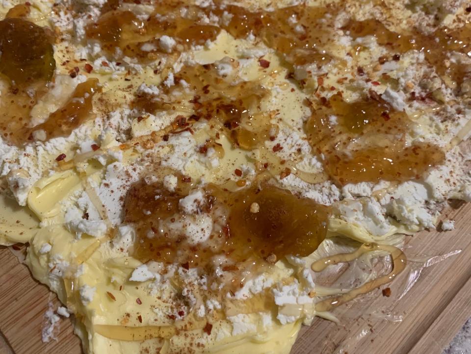 a butter board showing a thick layer of butter, fig jam, cinnamon, honey, and red pepper flakes