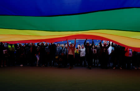 People hold a large rainbow flag during a protest in support of Elzbieta Podlesna, the author of an image depicting the Virgin Mary with a rainbow-coloured halo, reminiscent of the LGBT flag, who was detained for offending religious beliefs, in Warsaw, Poland May 7, 2019. REUTERS/Kacper Pempel