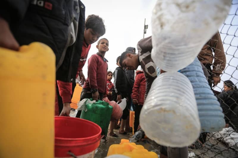 Displaced Palestinians line up to fill plastic containers from a water tank in in a camp for IDP near Rafah border crossing, amid the ongoing battles between Israel and the Palestinian Islamist group Hamas. Mohammed Talatene/dpa