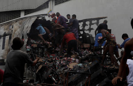 Residents loot a truck burned during violent clashes between rival gangs at a street near Brasil avenue near Cidade Alta slum in Rio de Janeiro, Brazil, May 2, 2017. REUTERS/Ricardo Moraes