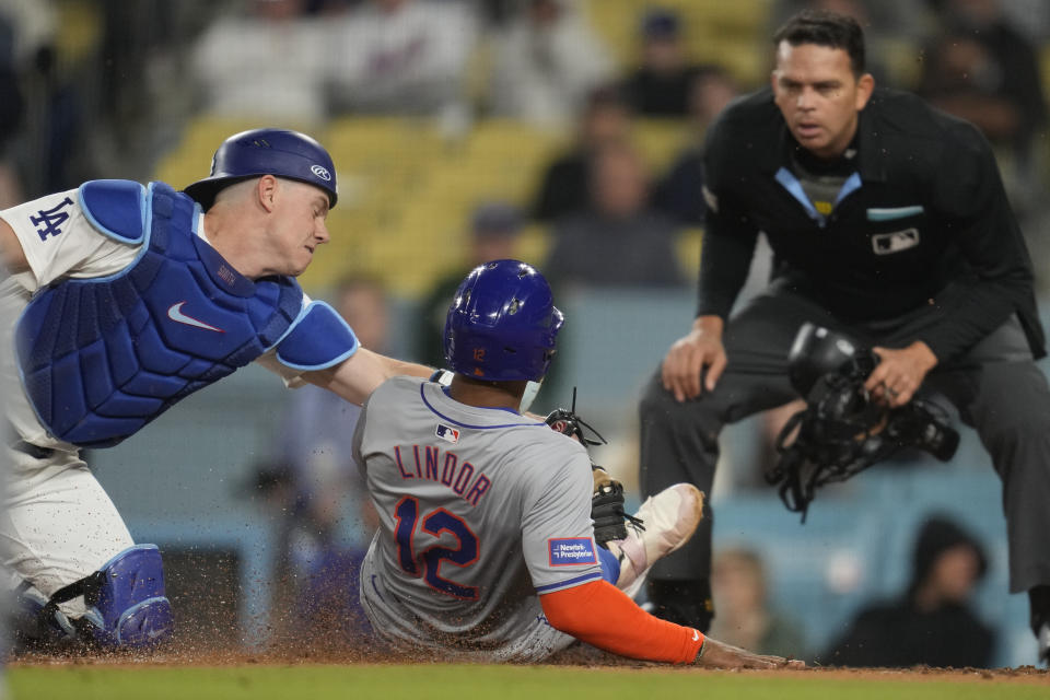 New York Mets' Francisco Lindor (12) scores off of a single hit by DJ Stewart during the ninth inning of a baseball game against the Los Angeles Dodgers in Los Angeles, Friday, April 19, 2024. Los Angeles Dodgers catcher Will Smith is at left. (AP Photo/Ashley Landis)