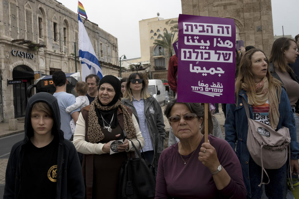 A Palestinian woman, center, takes part in a protest by Israelis in solidarity with Palestinians as part of ongoing protests against plans by Israeli Prime Minister Benjamin Netanyahu's government to overhaul the judicial system, in Jaffa, Israel, Thursday, March 23, 2023. The placard in Arabic and Hebrew reads: "This is home for all of us." Israel’s Palestinian minority has mostly sat out large protests against the government’s plan to overhaul the judiciary, a glaring absence in a battle to preserve Israel’s democratic ideals. The community may have the most to lose from the legal changes. (AP Photo/Maya Alleruzzo)