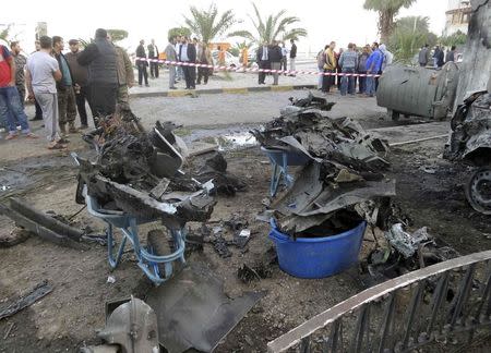 People and security stand at the scene of a car bomb explosion near the Egyptian embassy in the Libyan capital of Tripoli November 13, 2014. REUTERS/Stringer