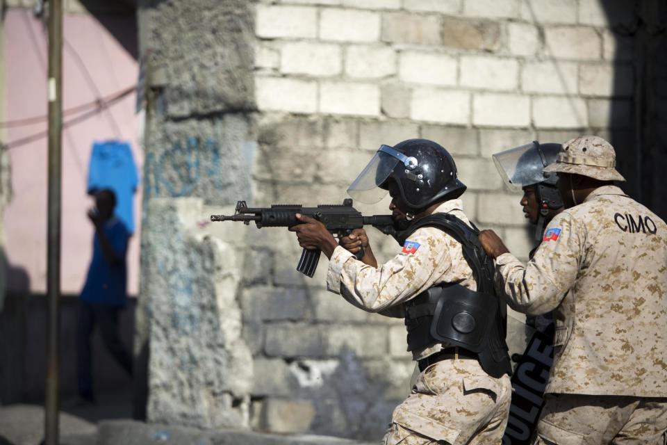 A national police officer points his gun at supporters of presidential candidate Maryse Narcisse protesting final election results in Port-au-Prince, Haiti, Tuesday, Jan. 3, 2017. An electoral tribunal certified the presidential election victory of first-time candidate Jovenel Moise. (AP Photo/Dieu Nalio Chery)