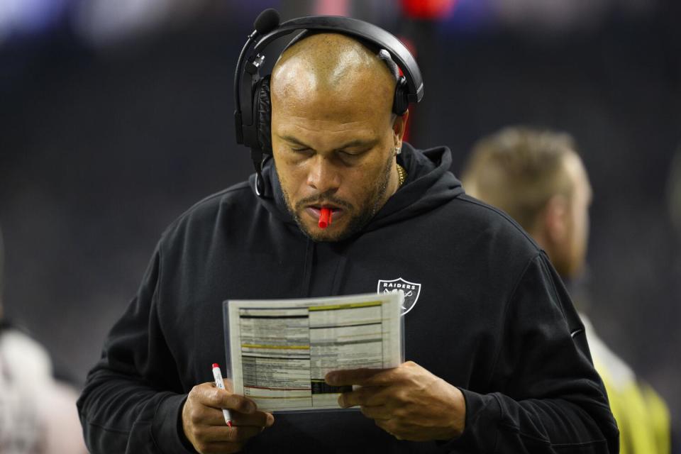 Raiders interim head coach Antonio Pierce studies his play sheet on the sideline.