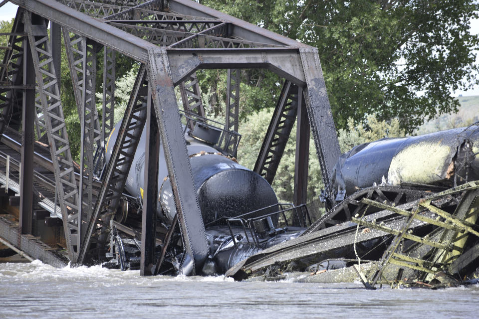 FILE - Several train cars are immersed in the Yellowstone River after a bridge collapse near Columbus, Mont., June 24, 2023. Two months after the collapse sent carloads of hazardous oil products plunging into the Yellowstone River, the cleanup workers are gone and a mess remains. (AP Photo/Matthew Brown, file)