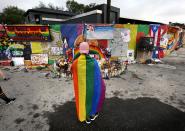 <p>A runner donning a gay pride flag pauses in front of the Pulse nightclub during the CommUNITYRainbowRun 4.9K road race, on Saturday, June 10, 2017, in Orlando, Fla. (Joe Burbank/Orlando Sentinel/TNS via Getty Images) </p>